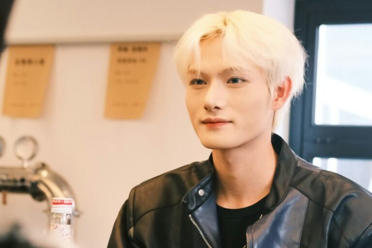 Man with platinum white dyed hair wearing a black jacket