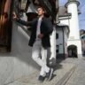 Well-dressed man leaning against a city building in a smart tailored outfit