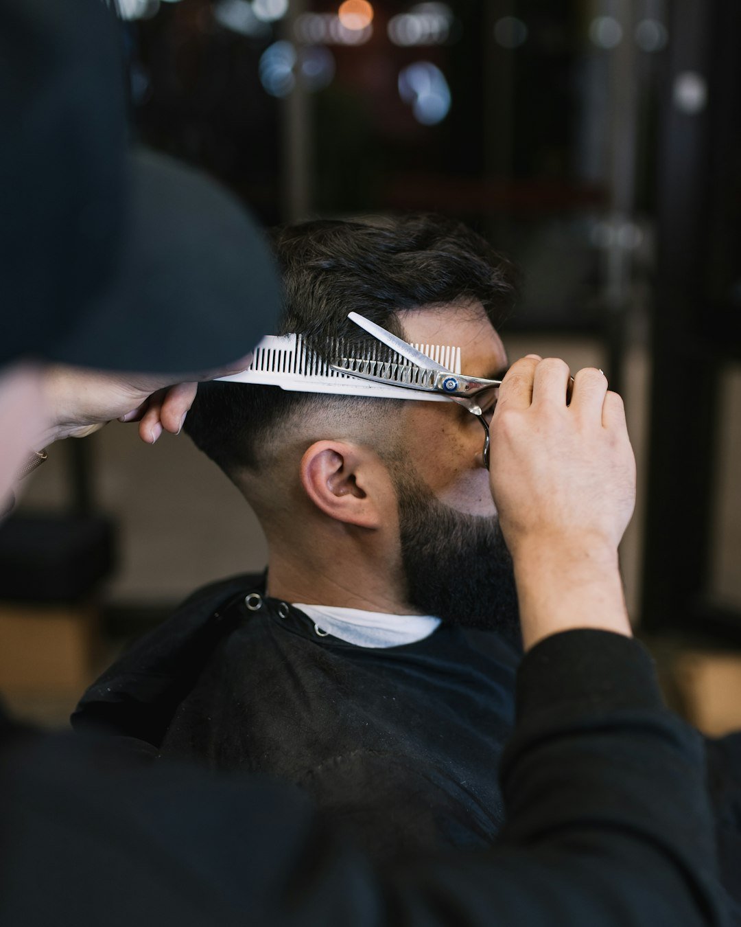 Barber cutting a man's hair with scissors